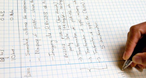 A Biotechnology Training Program Trainee writes in a lab notebook